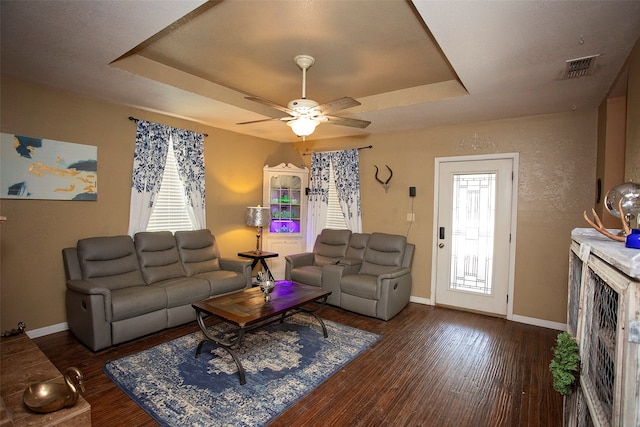 living room with ceiling fan, dark hardwood / wood-style floors, and a raised ceiling