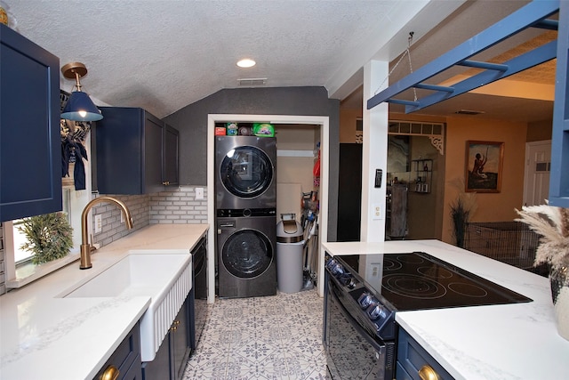 clothes washing area featuring a textured ceiling, sink, and stacked washing maching and dryer