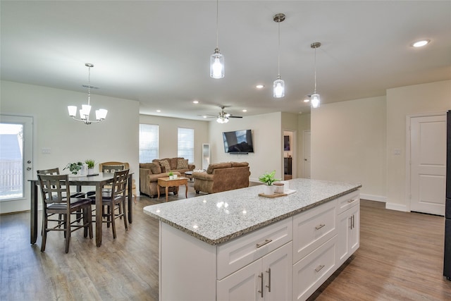 kitchen with ceiling fan, hanging light fixtures, a kitchen island, white cabinetry, and light wood-type flooring