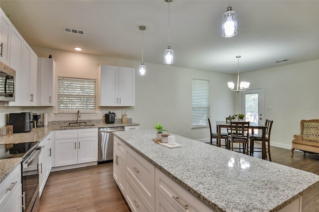 kitchen with dark wood-type flooring, white cabinets, appliances with stainless steel finishes, and a kitchen island