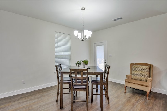 dining area with hardwood / wood-style floors and an inviting chandelier