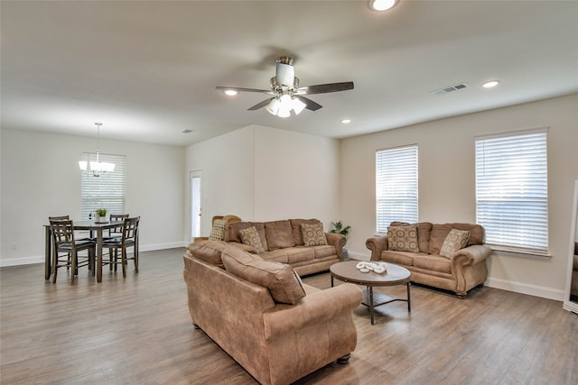 living room featuring ceiling fan with notable chandelier and light hardwood / wood-style floors