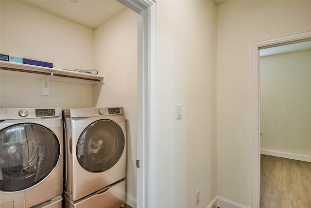 washroom featuring washing machine and dryer and light hardwood / wood-style flooring