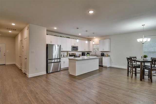 kitchen featuring a kitchen island, dark hardwood / wood-style flooring, pendant lighting, white cabinetry, and appliances with stainless steel finishes