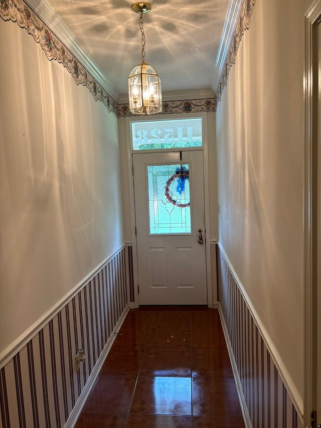 doorway with dark tile patterned floors, crown molding, a textured ceiling, and a chandelier