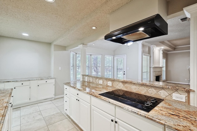 kitchen with ornate columns, extractor fan, white cabinets, and black electric stovetop