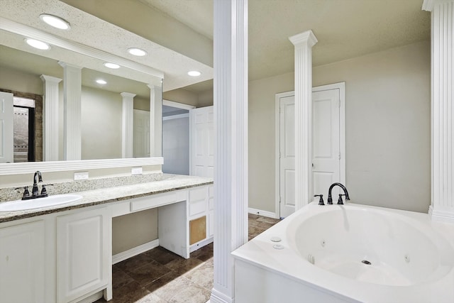 bathroom featuring vanity, a textured ceiling, decorative columns, and a washtub