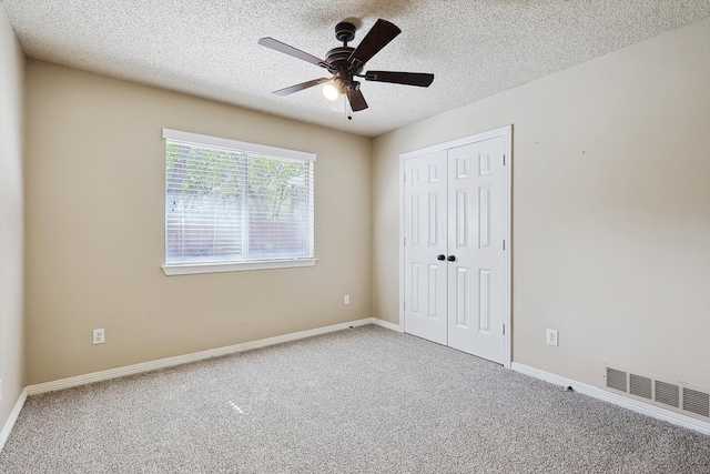 unfurnished bedroom featuring carpet flooring, a textured ceiling, and ceiling fan