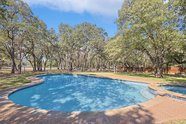 view of swimming pool featuring a lawn and an in ground hot tub