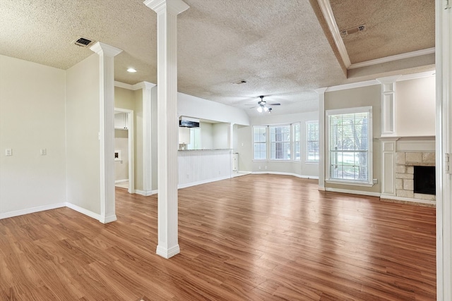 unfurnished living room featuring ceiling fan, a stone fireplace, ornamental molding, hardwood / wood-style flooring, and a textured ceiling