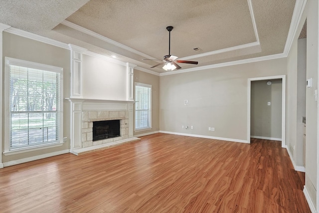 unfurnished living room with a tray ceiling, plenty of natural light, and hardwood / wood-style floors