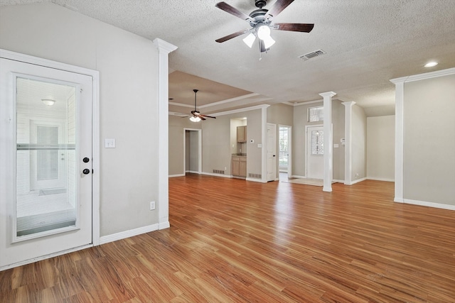 unfurnished living room featuring ceiling fan, a textured ceiling, light hardwood / wood-style floors, and decorative columns