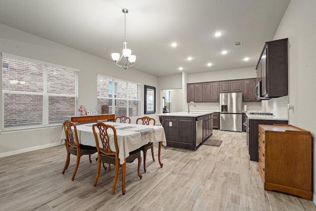 dining area with sink, a notable chandelier, and light hardwood / wood-style floors