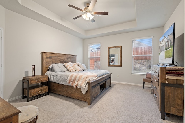 carpeted bedroom featuring a raised ceiling, multiple windows, and ceiling fan