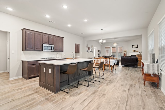 kitchen featuring stainless steel appliances, a breakfast bar area, light wood-type flooring, and a kitchen island with sink