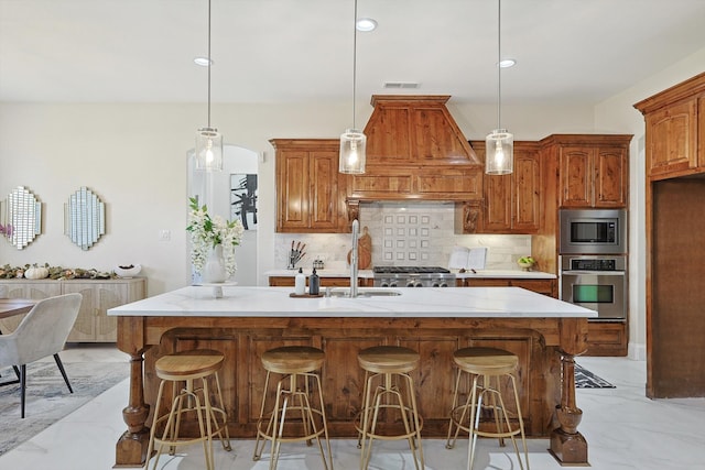 kitchen featuring backsplash, a center island with sink, stainless steel appliances, and decorative light fixtures