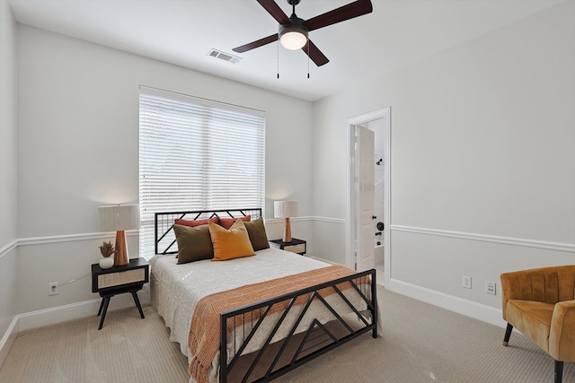 bedroom featuring light carpet, ensuite bathroom, and ceiling fan