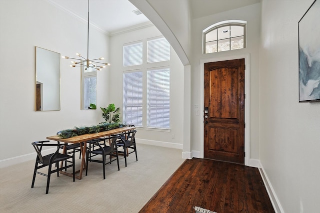 foyer with a towering ceiling, carpet, a chandelier, and ornamental molding