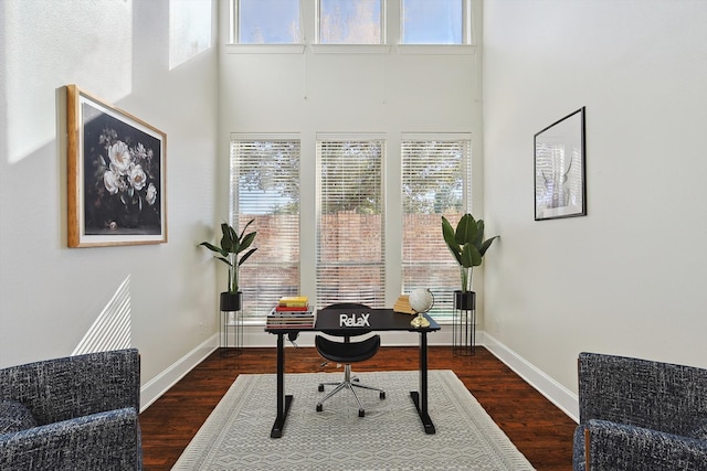 home office featuring dark wood-type flooring and a high ceiling