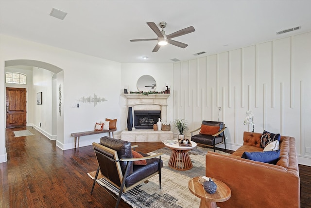 living room featuring dark hardwood / wood-style floors, ceiling fan, and a tiled fireplace