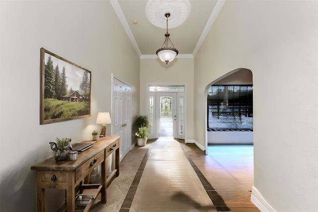 entryway with a towering ceiling, crown molding, and dark hardwood / wood-style floors