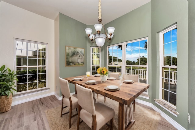 dining space with light hardwood / wood-style floors and an inviting chandelier