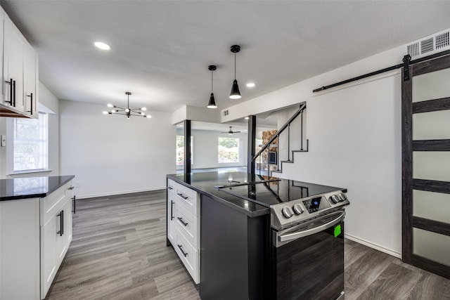 kitchen featuring a barn door, hanging light fixtures, white cabinets, and hardwood / wood-style floors