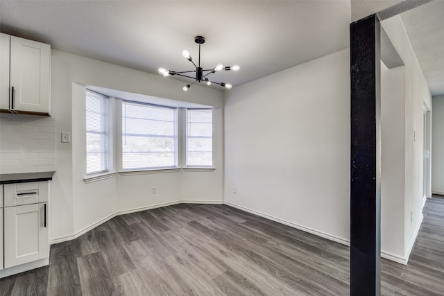 unfurnished dining area with an inviting chandelier and dark hardwood / wood-style flooring