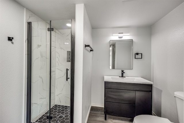 bathroom with wood-type flooring, a shower with shower door, vanity, and toilet