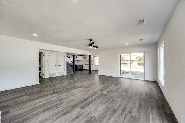 unfurnished living room featuring dark wood-type flooring and ceiling fan