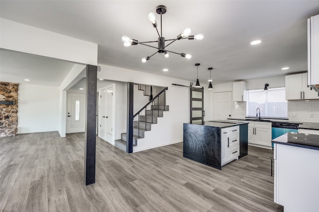 kitchen with white cabinets, light wood-type flooring, and hanging light fixtures