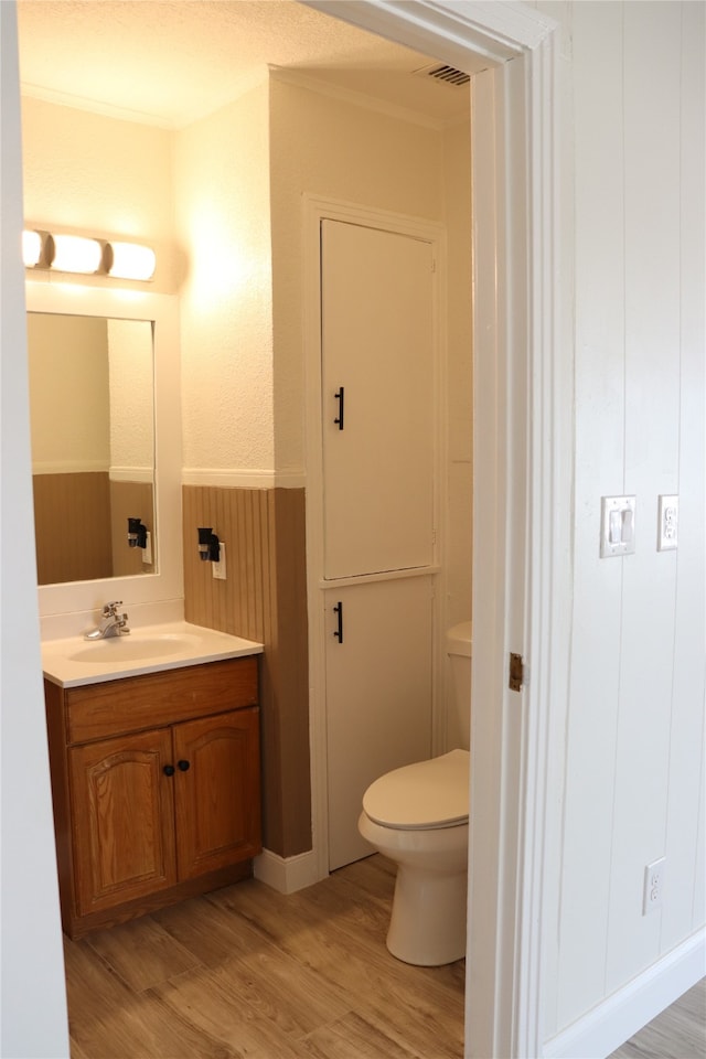 bathroom with ornamental molding, hardwood / wood-style flooring, toilet, and vanity