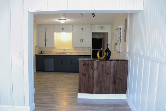 kitchen featuring sink, backsplash, white cabinetry, black double oven, and hardwood / wood-style floors