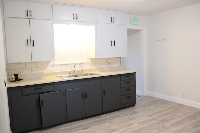 kitchen featuring light hardwood / wood-style flooring, decorative backsplash, sink, and white cabinets