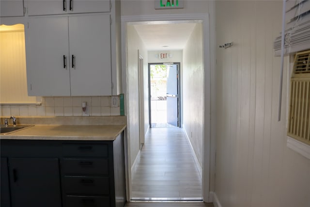 kitchen with white cabinets, sink, light hardwood / wood-style floors, and decorative backsplash