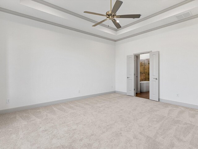 carpeted spare room featuring ornamental molding, a tray ceiling, and ceiling fan