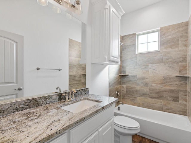 full bathroom featuring vanity, tiled shower / bath, wood-type flooring, and toilet