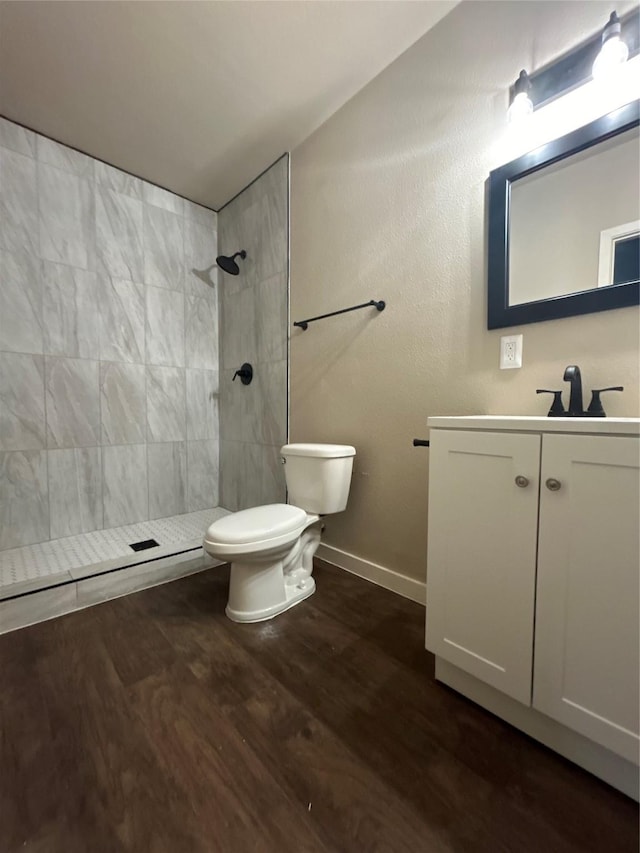 bathroom with vanity, wood-type flooring, toilet, and a tile shower