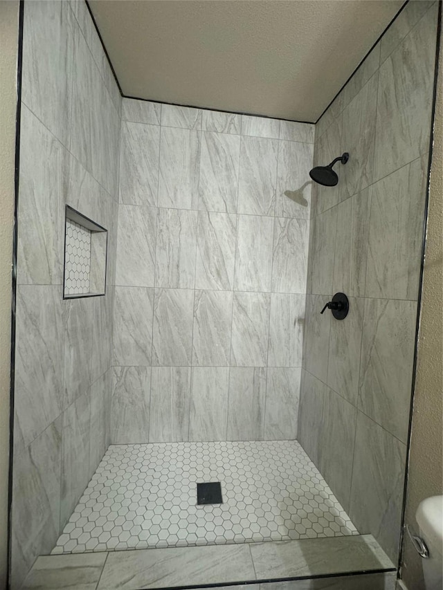 bathroom with a tile shower and toilet