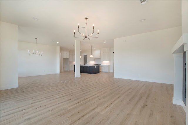 unfurnished living room featuring a notable chandelier and light hardwood / wood-style flooring