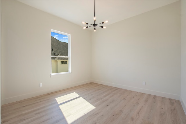 spare room featuring an inviting chandelier and light hardwood / wood-style floors