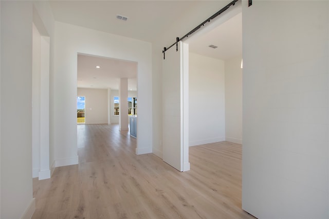 hall featuring a barn door and light hardwood / wood-style flooring