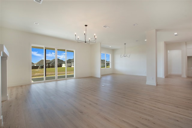 unfurnished living room with an inviting chandelier and light wood-type flooring