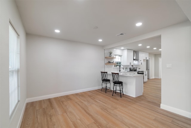 kitchen featuring kitchen peninsula, a kitchen bar, a wealth of natural light, and white cabinetry