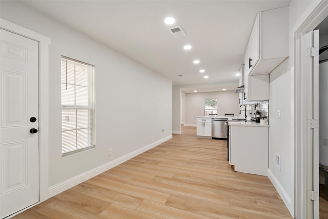 kitchen with a wealth of natural light, white cabinetry, light hardwood / wood-style floors, and dishwasher