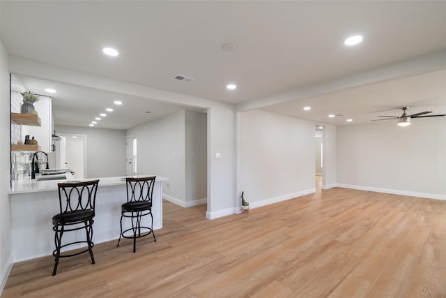 kitchen with kitchen peninsula, white cabinetry, a kitchen breakfast bar, and light hardwood / wood-style flooring