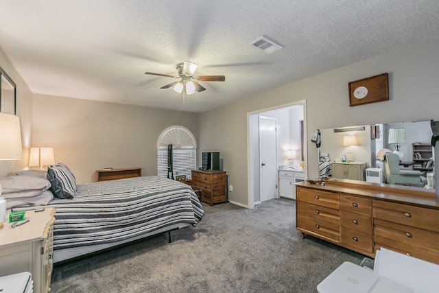 bedroom with ensuite bathroom, ceiling fan, dark carpet, and a textured ceiling