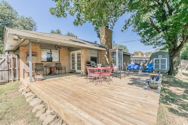 wooden deck with ceiling fan, a grill, and a storage unit