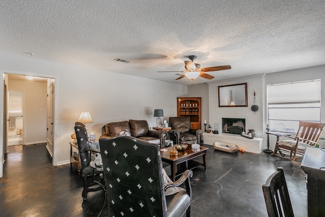 living room featuring a brick fireplace, ceiling fan, and a textured ceiling