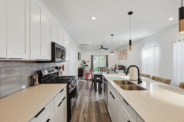 kitchen with appliances with stainless steel finishes, sink, pendant lighting, white cabinets, and dark hardwood / wood-style floors